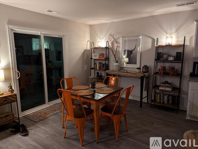 A dining room with a table set for two and a bookshelf in the background.