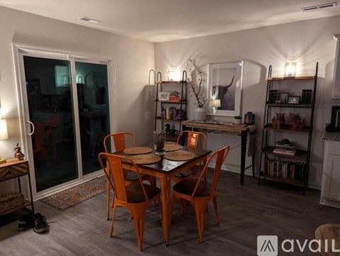 A dining room with a table set for two and a bookshelf in the background.