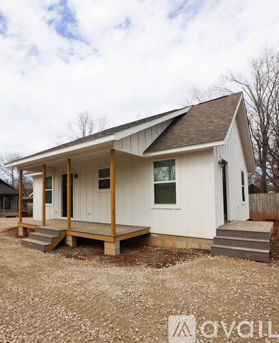 A small white house with a porch and a brown roof.