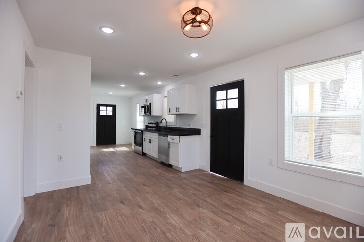A modern kitchen with white walls and wooden floors.