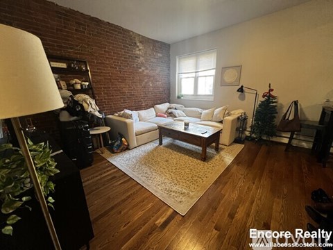 A living room with a white couch and a wooden floor.
