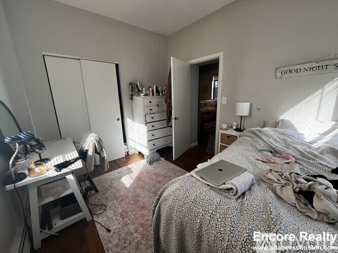 A bedroom with a bed, dresser, and a sign on the wall that says "Good Night".
