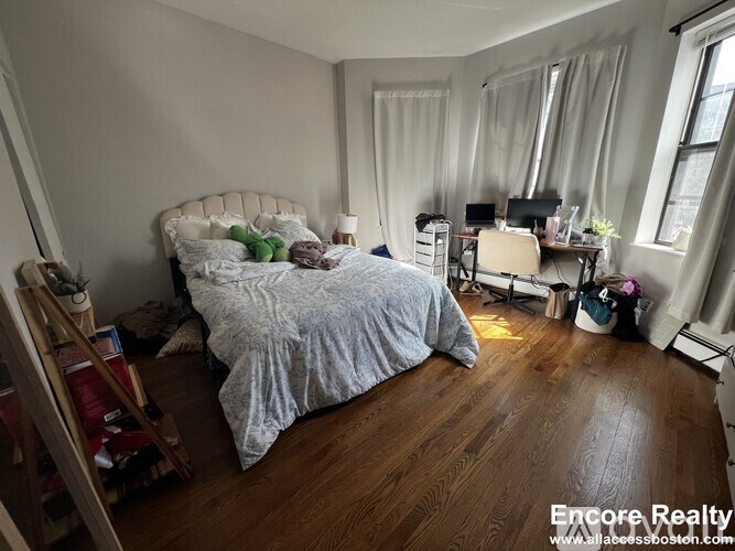 A bedroom with a bed, desk, and chair.