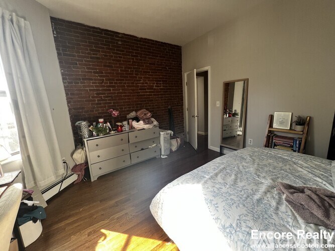 A bedroom with a brick wall and a large bed.