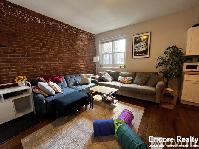 A living room with a brick wall and a grey couch.