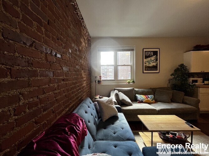 A living room with a blue couch and a red pillow.