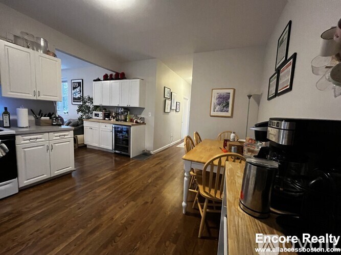 A kitchen with white cabinets and a wooden floor.
