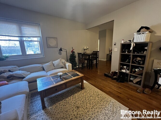 A living room with a couch, coffee table, and a dining table.