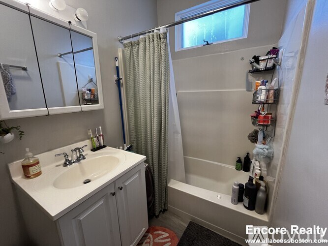 A white sink with a bottle of soap on it.