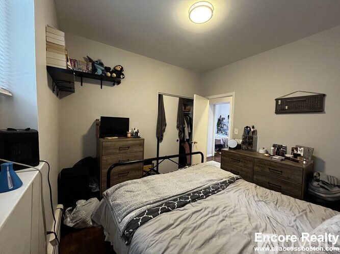 A bedroom with a bed, dresser, and window.