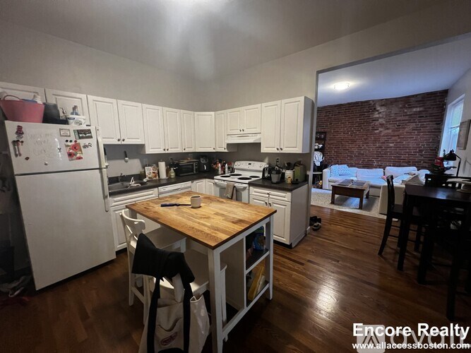 A kitchen with white cabinets and a wooden table.