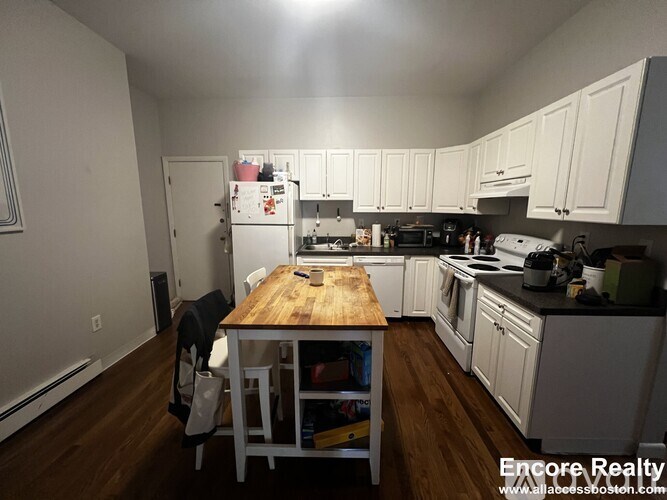 A kitchen with white cabinets and a wooden table.