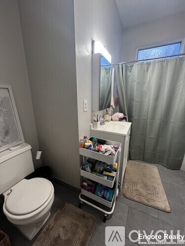 A bathroom with a white toilet and a shelf with various items on it.