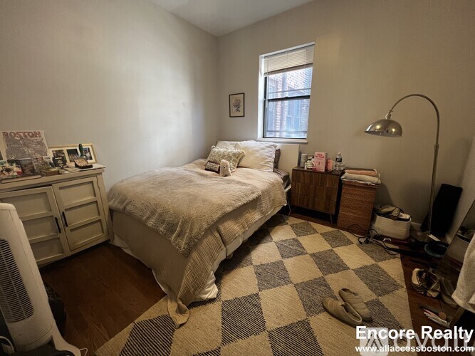 A bedroom with a bed, nightstand, and window.