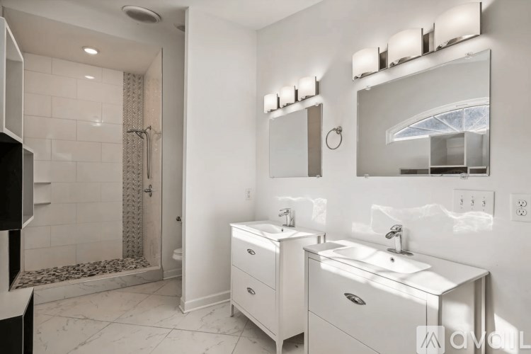 A white bathroom with a sink, mirror, and shower.