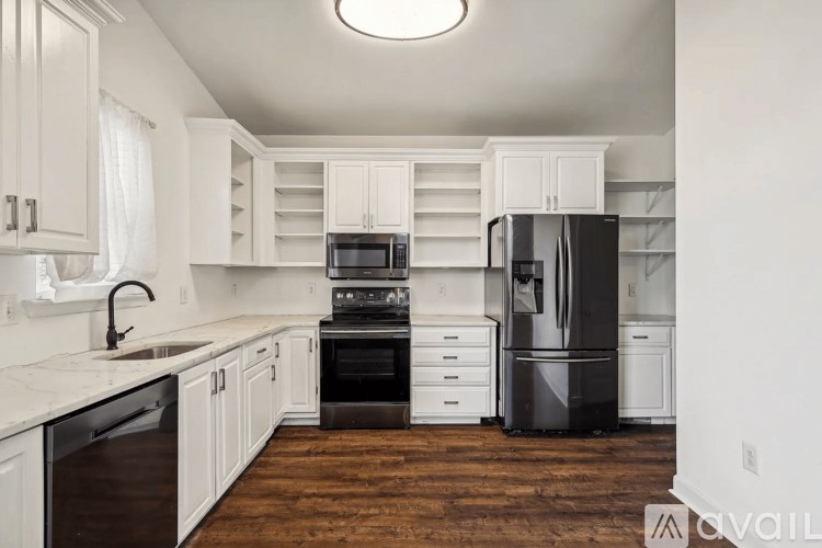 A kitchen with white cabinets and a black refrigerator.