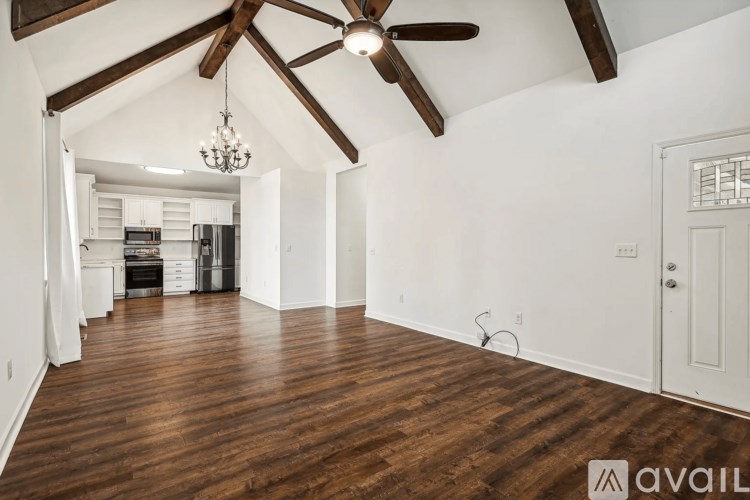 A spacious room with wooden floors and a ceiling fan.
