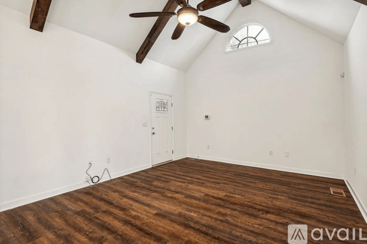 A room with a ceiling fan and a wooden floor.