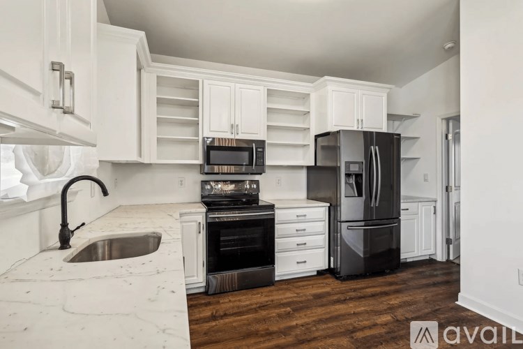 A kitchen with black appliances and white cabinets.