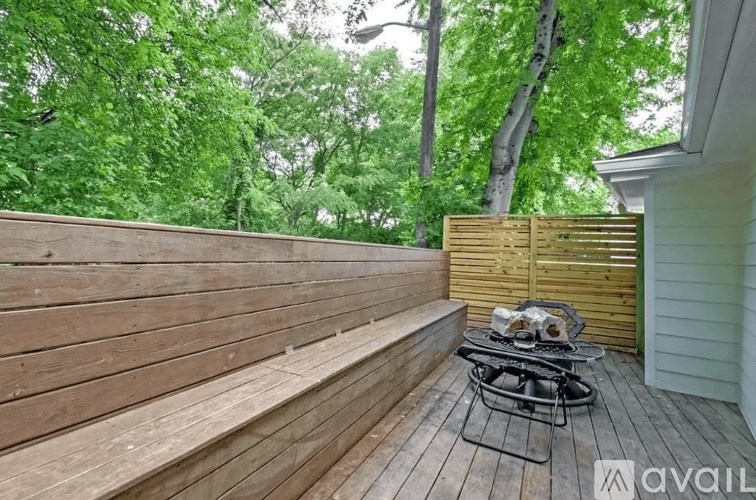 A wooden deck with a table and chairs is surrounded by green trees.