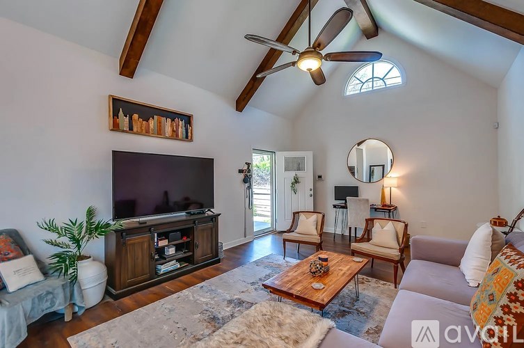 A living room with a ceiling fan and a flat screen TV.