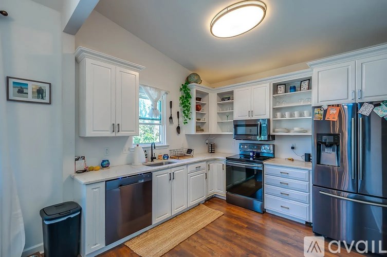 A kitchen with white cabinets and a black fridge.