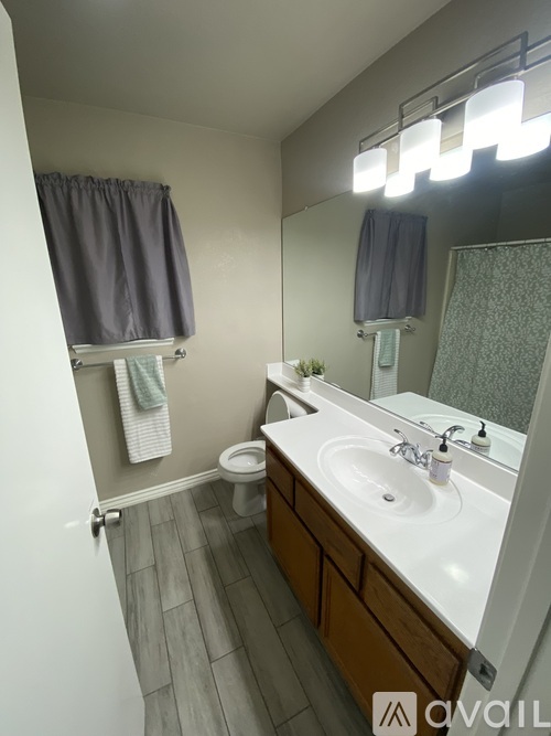 A bathroom with a large mirror, two sinks, and a window with curtains.