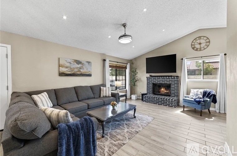 A living room with a grey sofa, a fireplace, and a TV mounted on the wall.