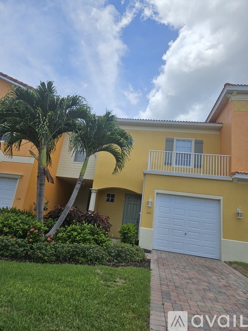 A yellow house with a blue garage door and a palm tree in front.