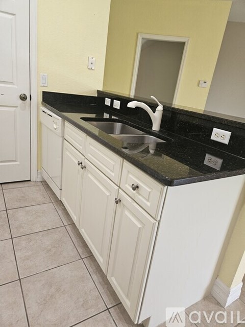 A kitchen with white cabinets and a black countertop.