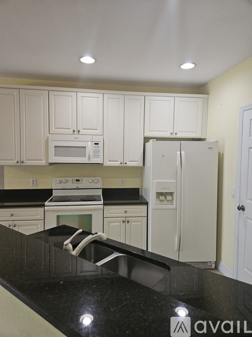 A kitchen with black countertops and white cabinets.