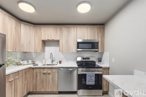 A kitchen with wooden cabinets and stainless steel appliances is available for rent.