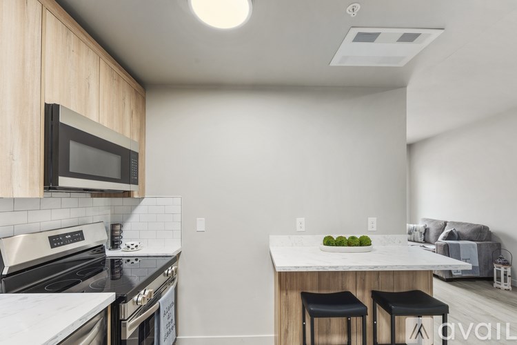 A kitchen with a stove, microwave, and bar stools.