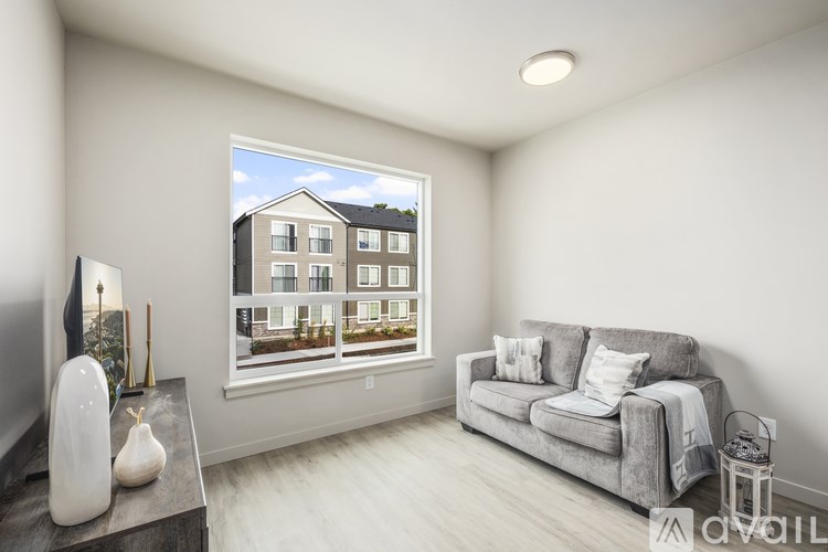 A living room with a grey couch, a white vase, and a television.