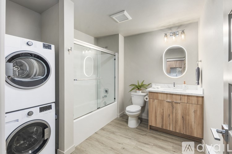 A modern bathroom with a washing machine next to the toilet.