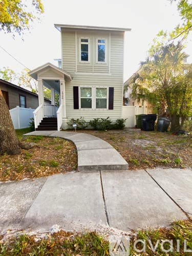 A beige house with a white fence and a small front yard.