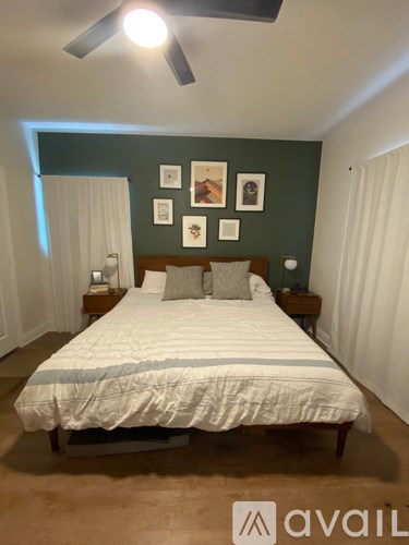 A bedroom with a bed, nightstands, and pictures on the wall.