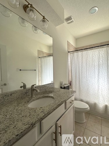 A bathroom with granite countertops and a shower curtain.
