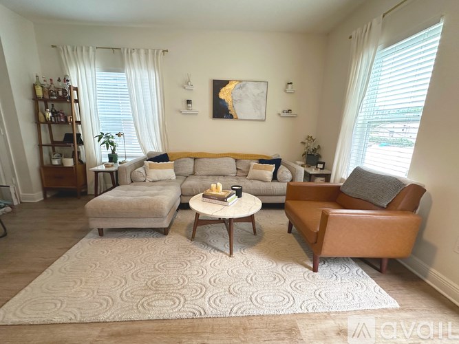 A living room with a grey sofa, a brown leather armchair, a wooden coffee table, and a patterned rug.