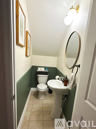 A bathroom with a toilet, sink, and mirror.