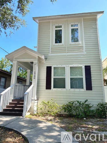 A two-story house with a front porch and a staircase leading to the entrance.