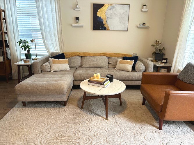 A living room with a grey sofa, a brown armchair, and a coffee table.