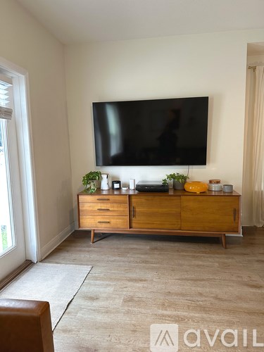 A living room with a flat screen TV mounted on the wall above a wooden cabinet.