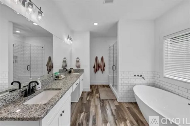 A bathroom with a white tub, sink, and wooden floor.