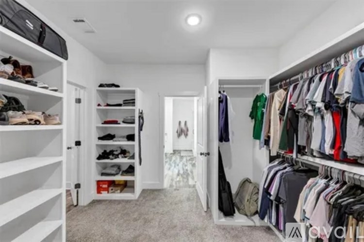 A white walk-in closet with clothes and shoes organized on shelves and hanging on racks.