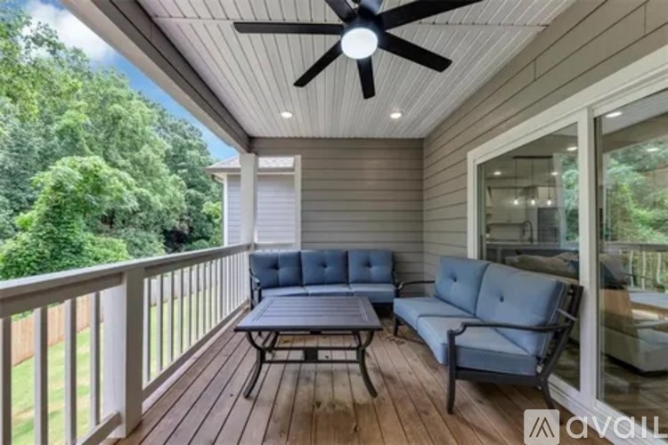 A balcony with a sofa, chairs, and a ceiling fan.