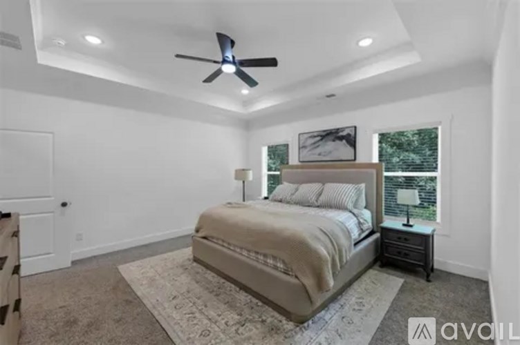 A bedroom with a large bed and a ceiling fan.