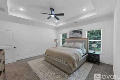 A bedroom with a large bed and a ceiling fan.