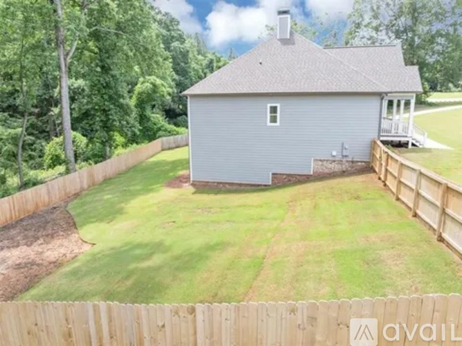 A house with a grey roof and a wooden fence in front of it.