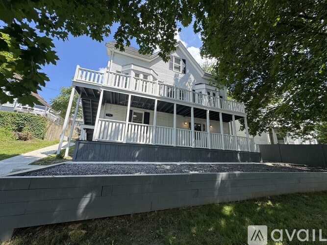 A white house with a porch and a balcony is shown.